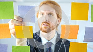 Redhead Man Working On Sticky Notes Attached on Glass in Office