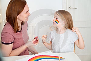 Mom draws child of rainbow on cheek. stay home. photo