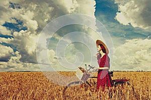 Peasant girl with bicycle on wheat field.