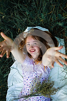 Redhead portrait of a beautiful young sexy red-haired woman, lying in the spring sun, relaxing on the green grass.