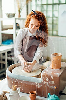 Redhead potter shaping clay in pottery studio