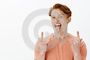 Redhead rule world. Portrait of charming rebellious and confident ginger male with freckles, sticking out tongue and