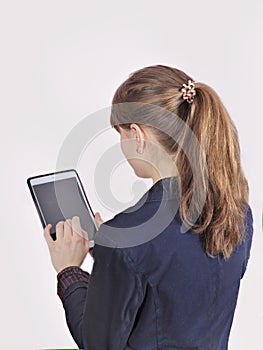 Redhead schoolgirl is holding digital tablet with empty blank screen. isolated over a grey background.