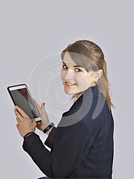 Redhead schoolgirl is holding digital tablet with empty blank screen. isolated over a grey background