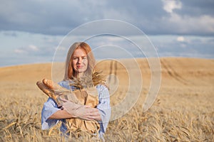 Redhead woman with bakery products in ripe wheat field