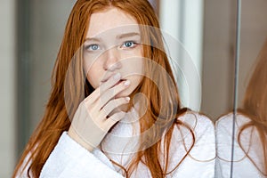 Redhead woman in bathrobe looking at camera