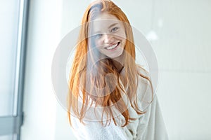 Redhead woman in bathrobe looking at camera