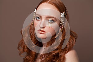 Redhead woman with creative makeup on brown background