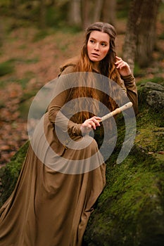 Redhead woman in dress walking in fantasy fairy tale forest