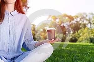 Redhead woman drinking coffee in summer park