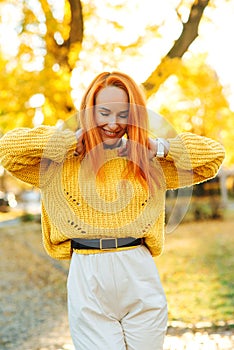 Redhead woman enjoying life outdoors. Happy woman walking in autumn park. Autumn fashion, lifestyle and holidays