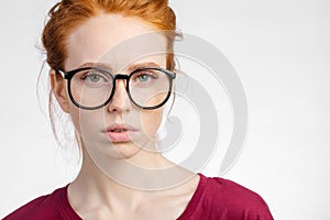 Redhead woman in glasses with hair knot looking at camera on white background