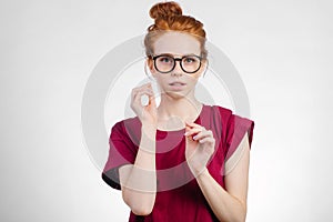 Redhead woman in glasses with hair knot looking at camera on white background