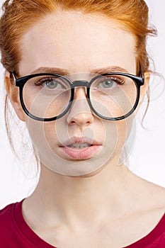 Redhead woman in glasses with hair knot looking at camera on white background