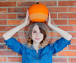 Redhead woman in jeans clothes holding orange autumn pumpkin