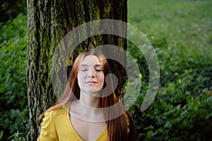 Redhead Woman Leaning On Tree Smiling With Closed Eyes