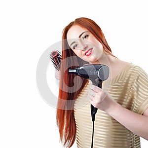 Redhead woman with long hair holding hair dryer and comb