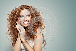 Redhead woman with long healthy curly hair, clear skin and cute smile. Beautiful female face
