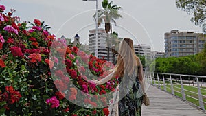 Redhead woman with a long is waking on a bridge with red flowers.