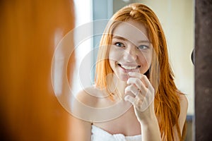 Redhead woman looking at her reflection in mirror