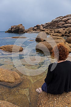 Testa rossa una donna guarda sul riva del mare 