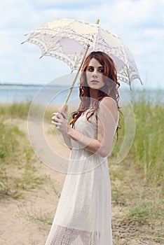 Redhead woman with parasol on beach trail