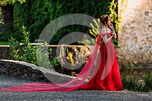 Redhead woman in red dress near the castle
