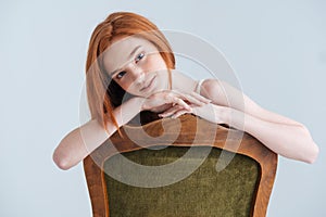 Redhead woman sitting on the chair and looking at camera