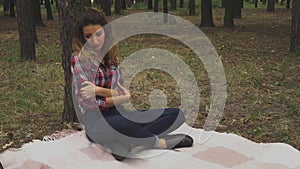 Redhead woman is sitting in the forest near the tree