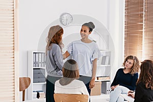 Redhead woman supporting sad friend during psychotherapy group meeting