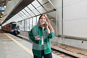 Redhead woman waiting train and using smart phone. Railroad transport concept, Traveler. 30s Middle age woman with