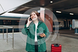 Redhead woman waiting train and using smart phone. Railroad transport concept, Traveler. 30s Middle age woman with red