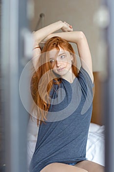 Redhead woman waking up and stretching hand