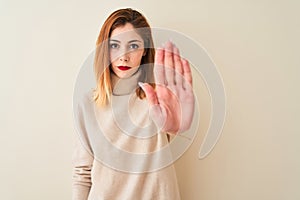 Redhead woman wearing elegant turtleneck sweater standing over isolated white background doing stop sing with palm of the hand