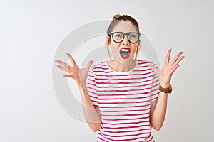 Redhead woman wearing glasses striped t-shirt and pigtail over isolated white background crazy and mad shouting and yelling with