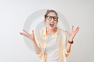 Redhead woman wearing striped shirt and glasses standing over isolated white background crazy and mad shouting and yelling with