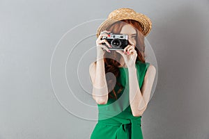 Redhead young lady photographer holding camera.