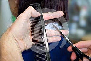 Redhead young woman getting haircut by man hairdresser, which does a bob hairstyle before dyeing.