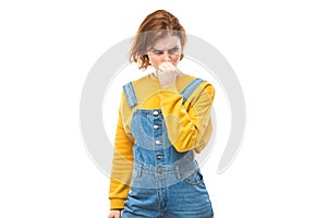 Redhead young woman holding nose to avoid disgusted smell, pinches nose and mouth with fingers and holding breath