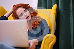 Redhead young woman using laptop at home. covid isolation. home office