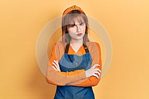 Redhead young woman wearing apron skeptic and nervous, disapproving expression on face with crossed arms photo