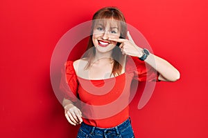 Redhead young woman wearing casual red t shirt pointing with hand finger to face and nose, smiling cheerful