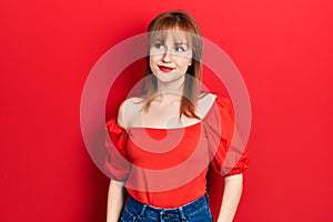 Redhead young woman wearing casual red t shirt smiling looking to the side and staring away thinking