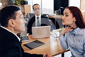 Redheaded angry woman argues with adult man in divorce lawyer`s office.