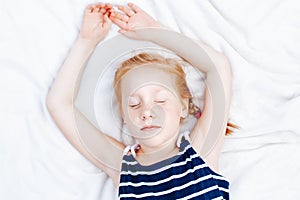 redheaded Caucasian child girl in striped nautical sleeveless shirt sleeping