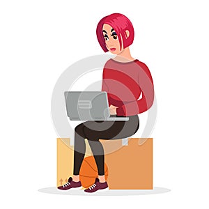 Redheaded girl sitting on cardboard box, looking for work or new flat, houseroom at laptop. photo