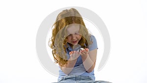 Redheaded little girl with curly hair is stroking decorative rat at white background. Slow motion