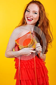 Redheaded smiling girl with orange handbag