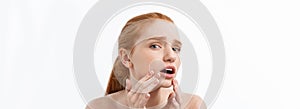 redheaded woman shows fingers on acne on her face.