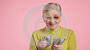 Rediculous old lady in stylish glasses counting dollars, can not believe in luck